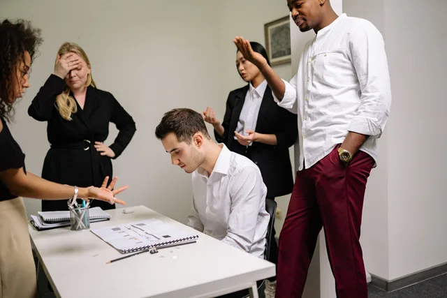 Business professionals engaged in a tense discussion at the office, highlighting workplace conflict. Arbejdspladskonflikter i SMV'er: regler og håndteringstrin