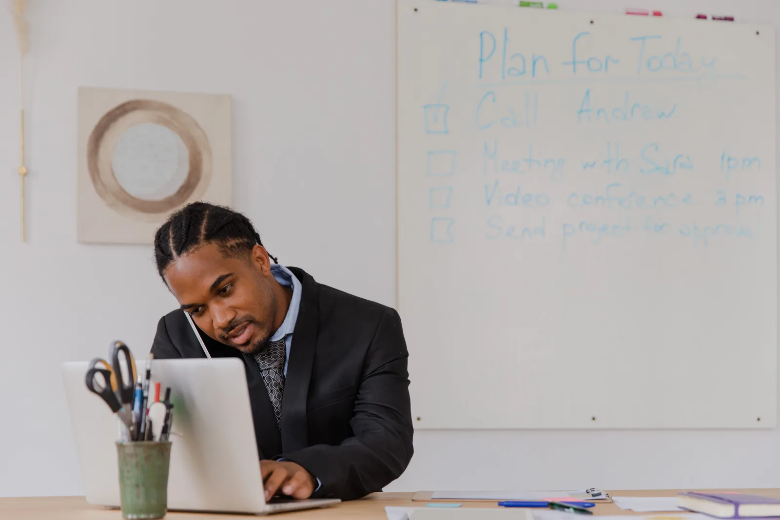 Businessman at his desk in an office working on a laptop and making phone calls.